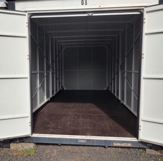 Inside an empty storage unit with the door rolled up.